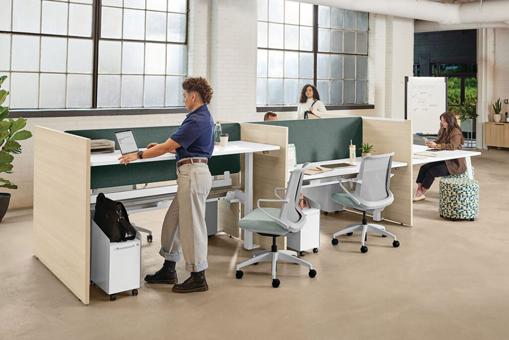 Person working at an adjustable height workstation with ergonomic chairs.