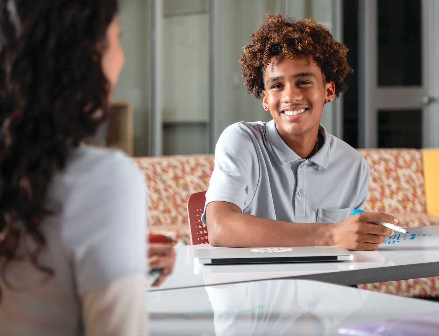 Cheerful student seated at desk collaborating with a classmate